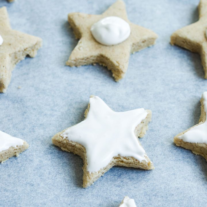 zimtsterne cookies cut into stars and being iced with meringue icing