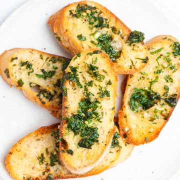 close up overhead of slices of air fryer garlic bread on a white plate