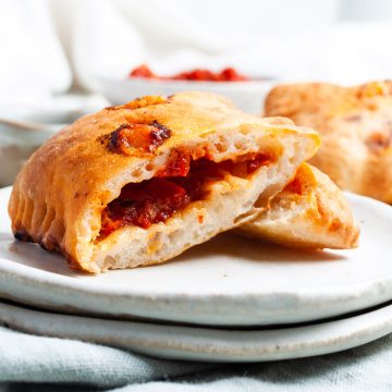 air fryer pizza rolls on a plate, cut in half to show spongy dough and tomato cheese filling
