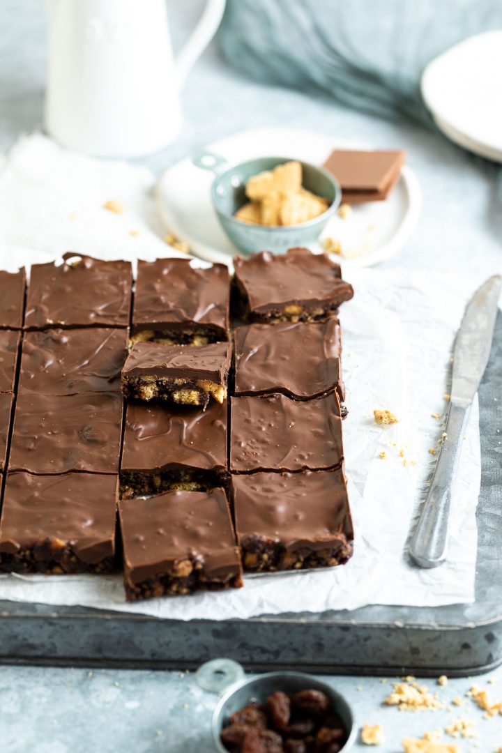 angled shot of the chocolate slice on a sheet of parchment on a tray, a knife to the side to show it's just been cut in to squares