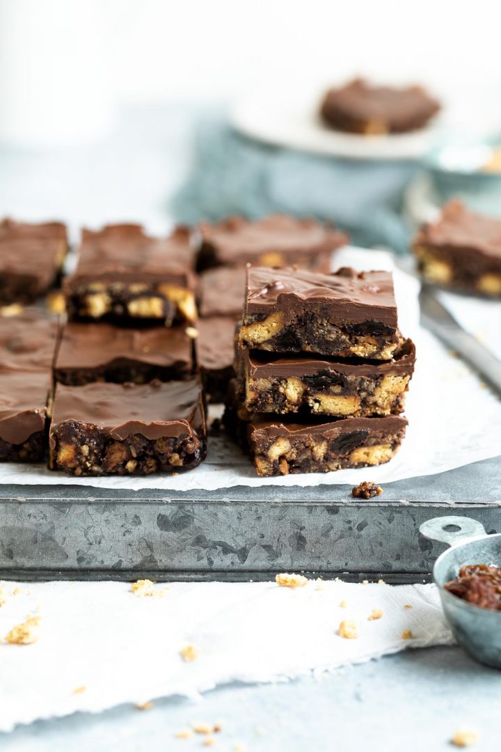 cut squares of the chocolate slice, 3 stacked, other pieces just visible behind