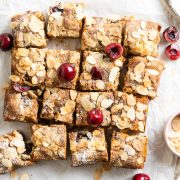 cut bakewell blondies decorated with fresh cherries and the surface scattered with flaked almonds