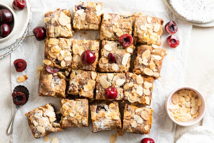 cut bakewell blondies decorated with fresh cherries and the surface scattered with flaked almonds
