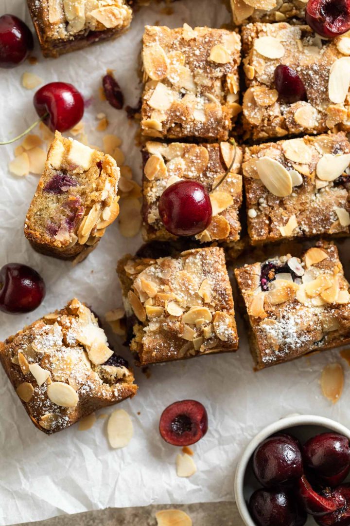 overhead close up of cut squares to show the almond topping, fresh cherries just visible.