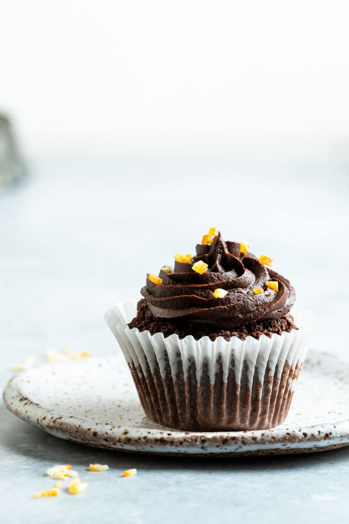 chocolate orange cupcake on a plate, candied orange pieces in front