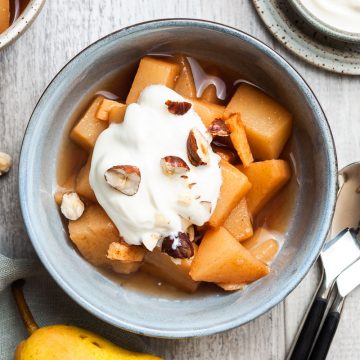 stewed pears in a bowl topped with yogurt and chopped hazelnuts