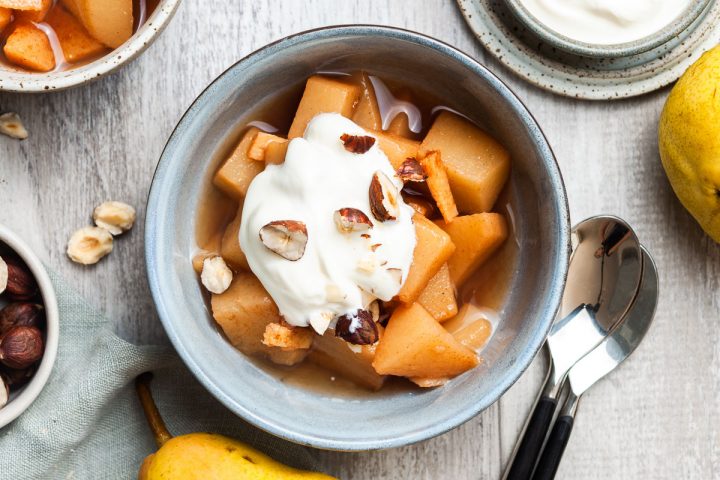 stewed pears in a bowl topped with yogurt and chopped hazelnuts