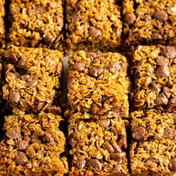 a batch of chocolate chip flapjacks on white background with chocolate chips to the right