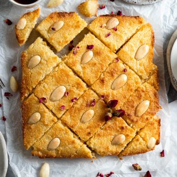 overhead photo of baked namoura sprinkled with rose petals and served with coffee