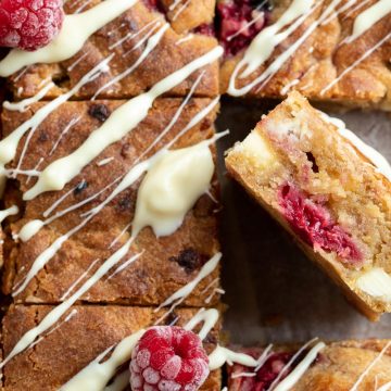 close up of cut side of raspberry white chocolate blondie to show chocolate chunks and raspberries