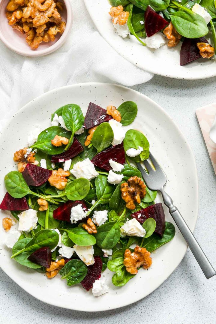 two plates of salad with extra honey walnuts in a bowl to sprinkle over the beetroot salad
