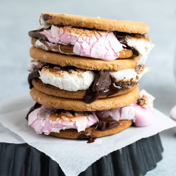 a stack of three digestive s'mores on an upturned baking tin showing the melted chocolate and oozing marshmallows