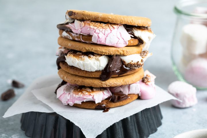 a stack of three digestive s'mores on an upturned baking tin showing the melted chocolate and oozing marshmallows