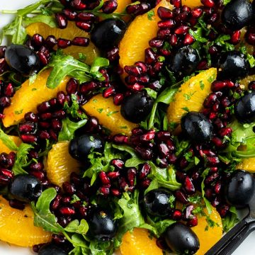 close up of Spanish orange salad with pomegranate and black olives on a serving plate