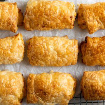 golden cooked cheese and onion rolls in rows on white background