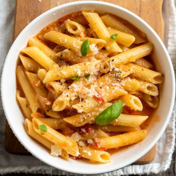 bowl of cooked one pot tomato pasta sprinkled with fresh basil leaves and sprinkled with cheese