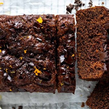 Two sliced cut from the end of the eggless chocolate orange cake to show orange syrup top of cake and open texture of chocolate cake