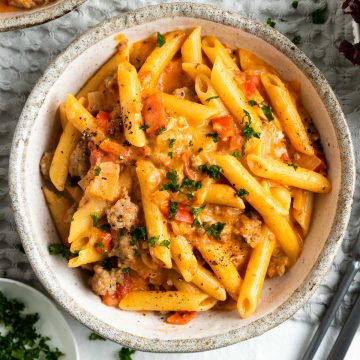 a bowl of creamy sausage pasta sprinkled with fresh parsley ready to eat