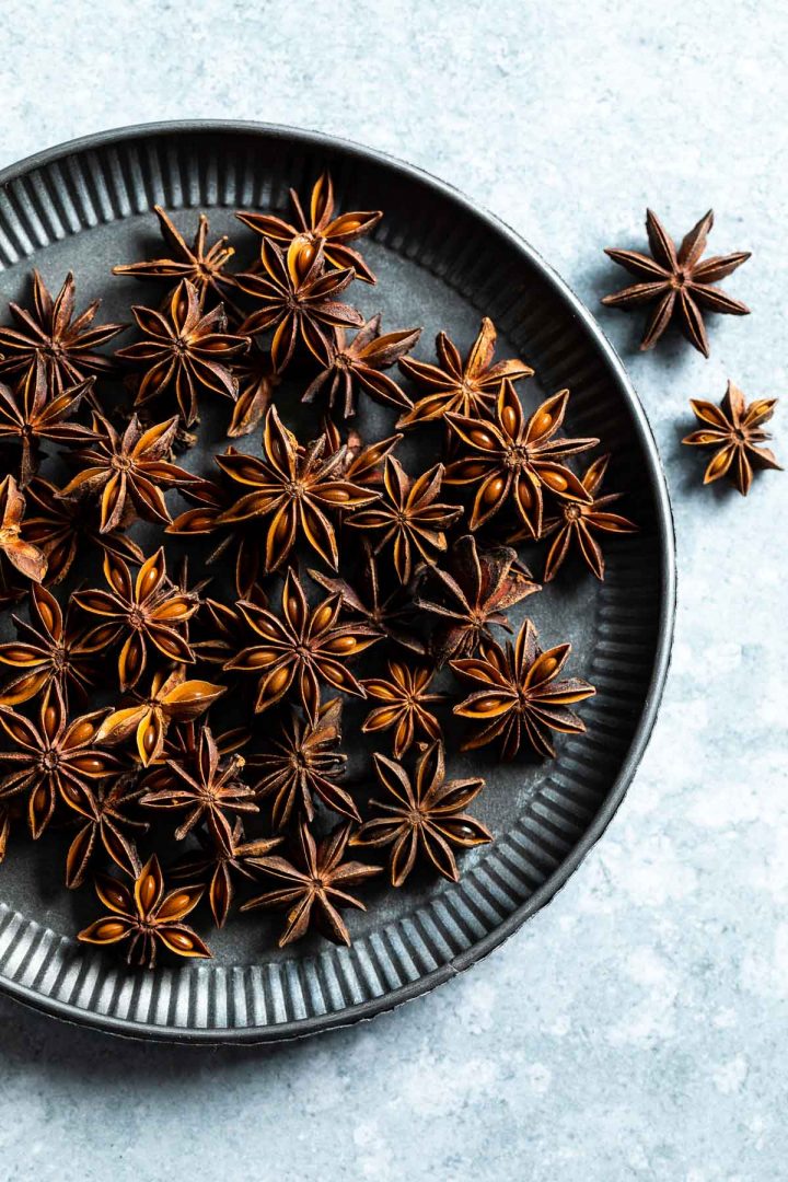 whole star anise seed pods on a metal plate, a couple of seed pods to the right of the plate