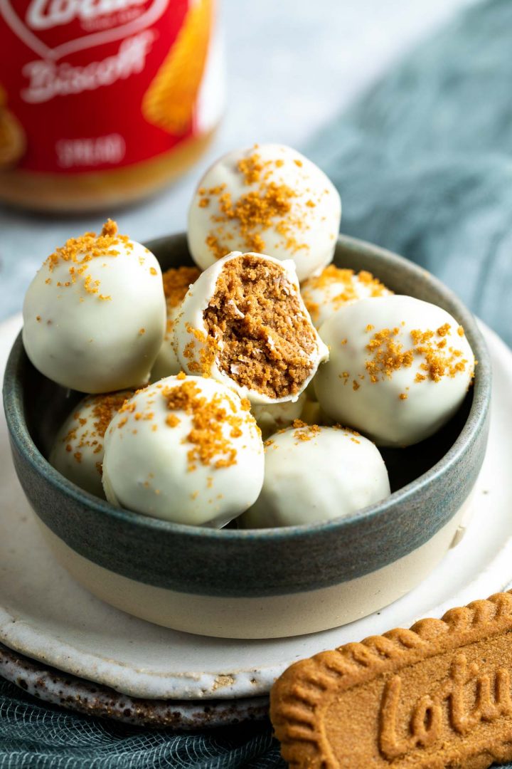 a bowl of Biscoff balls with white chocolate, the middle one has a bite taken out to show the texture.