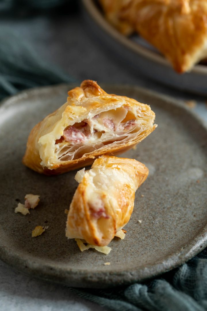 A puff pastry parcel cut in half on a plate to show the ham and cheese filling