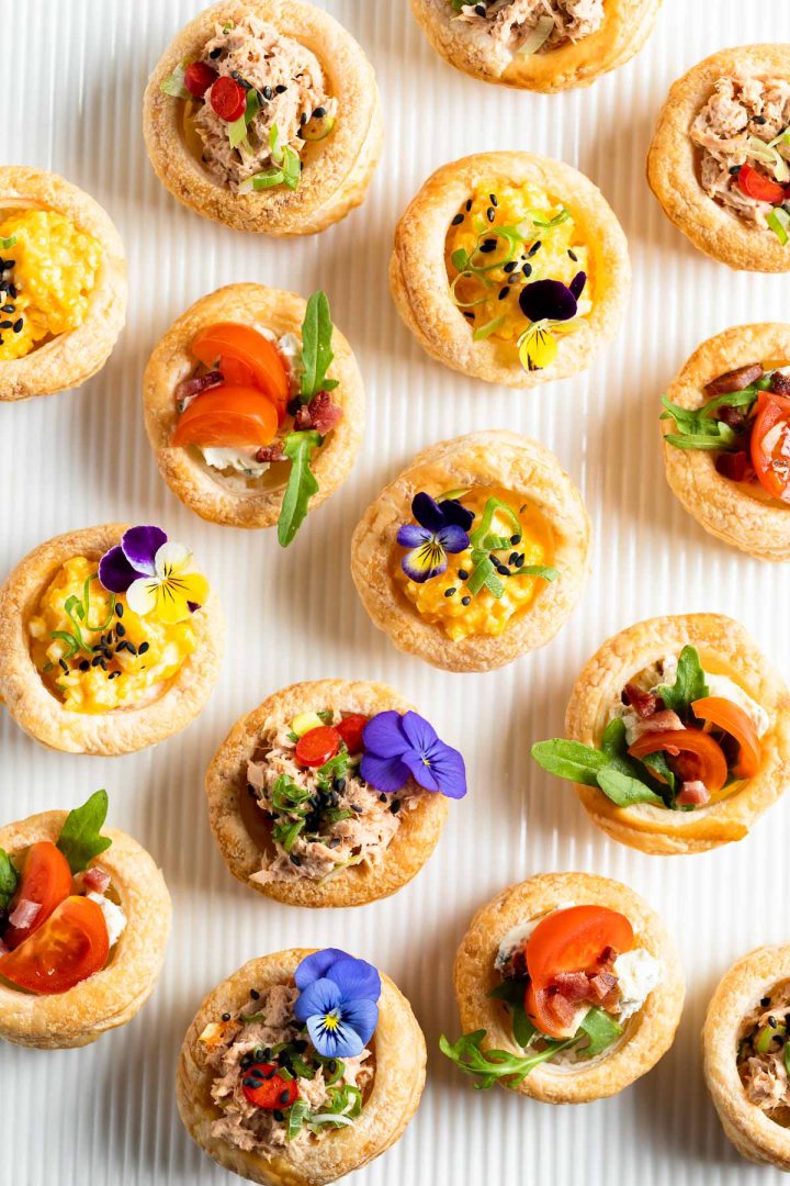 filled vol au vents decorated with edible flowers on white background