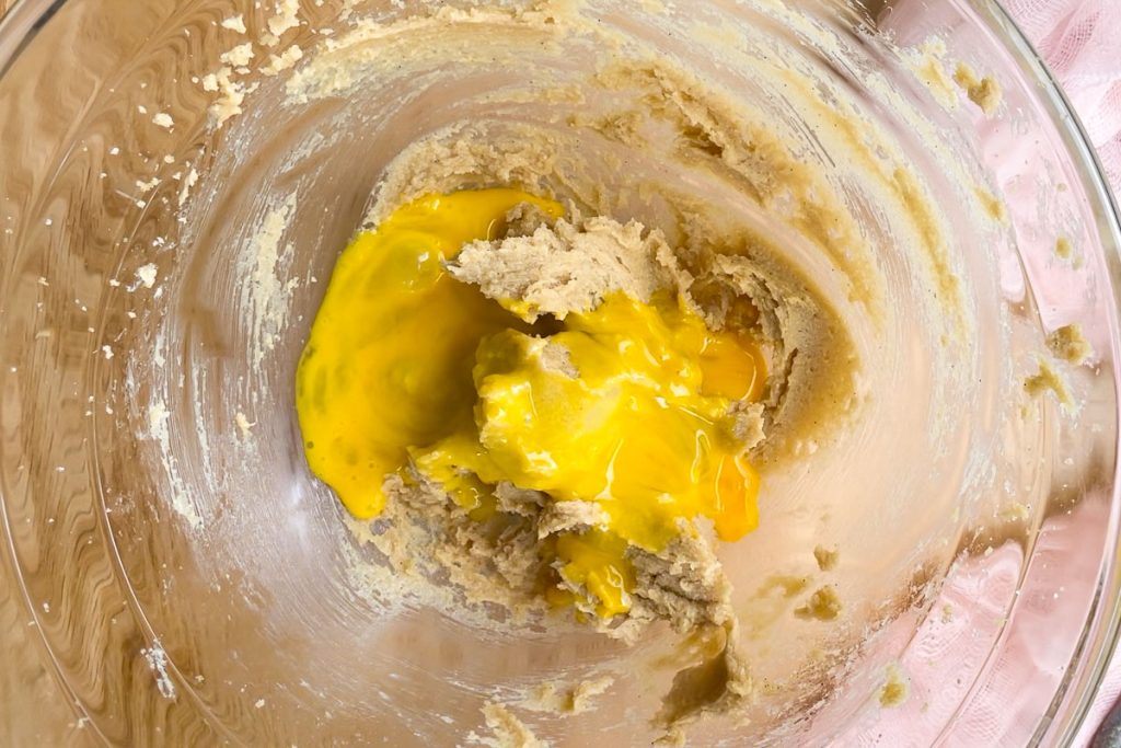 adding beaten egg to the whisked sugars and butter