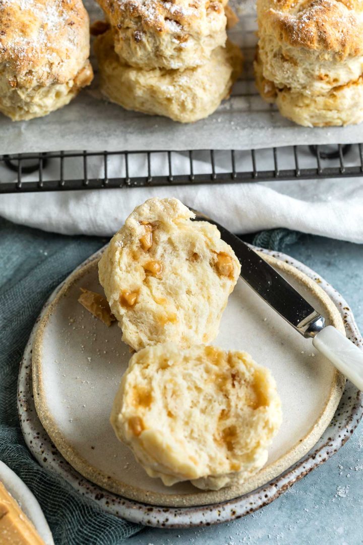 Scone cut in half on a plate to show the soft and fluffy texture and cubes of soft, melted caramilk dotted throughout the scone