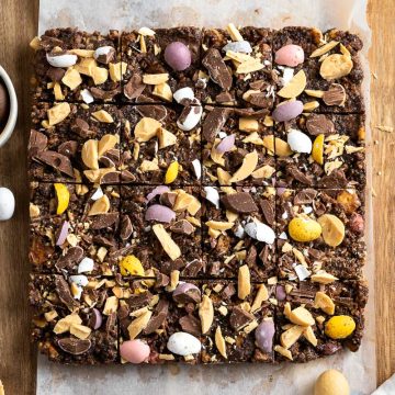 overhead view of Easter tiffin with a small bowl of mini Easter eggs to the left, other mini eggs scattered around and over the tiffin