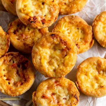 a pile of cooked muffin tin pizzas on white baking paper
