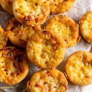 muffin tin pizza cups on white baking paper on wooden board ready to eat