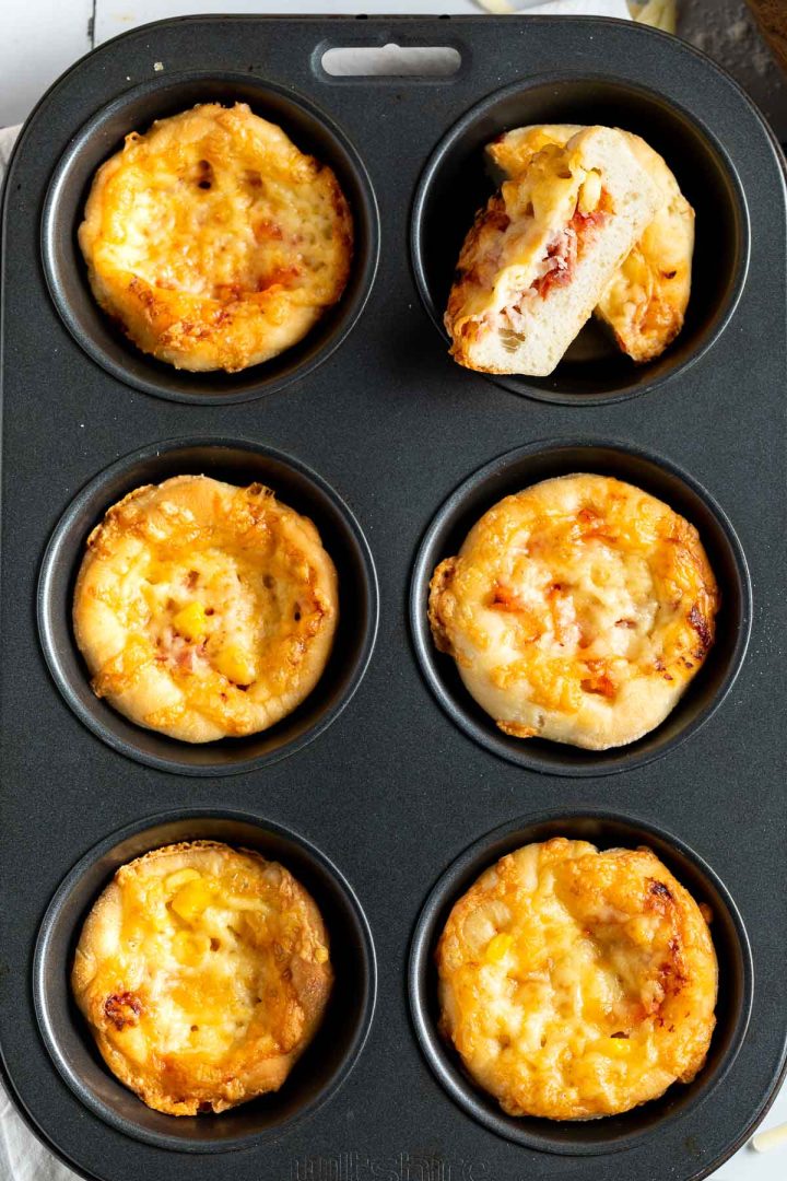 pizza cups in baking tin, the top right hand pizza cut in half to show soft fluffy dough