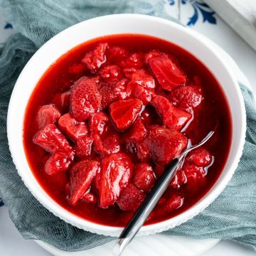 white bowl filled with strawberry compote, with a spoon in it ready to sesrve.
