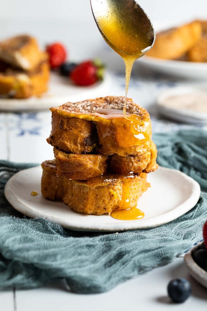 stack of Spanish style french toast on a plate being drizzled with honey.