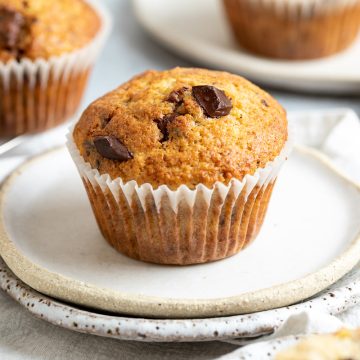 close up of a choc chip banana muffin on white plate.