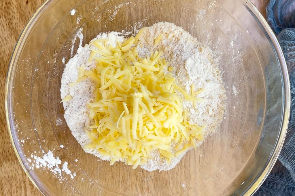 Grated cheese in the mixing bowl on top of the flour and butter.