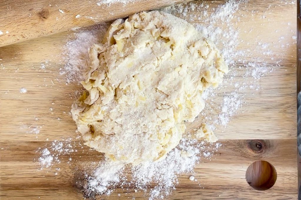 Scone dough on a floured wooden chopping board.