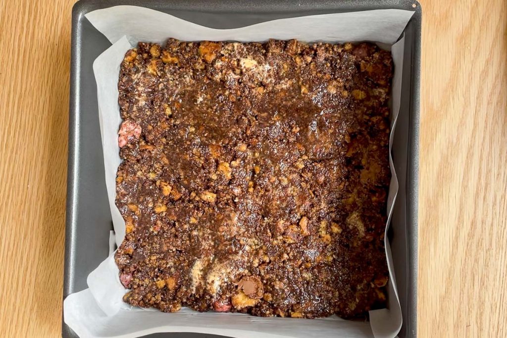The chocolate tiffin pressed down into a lined square baking tin.
