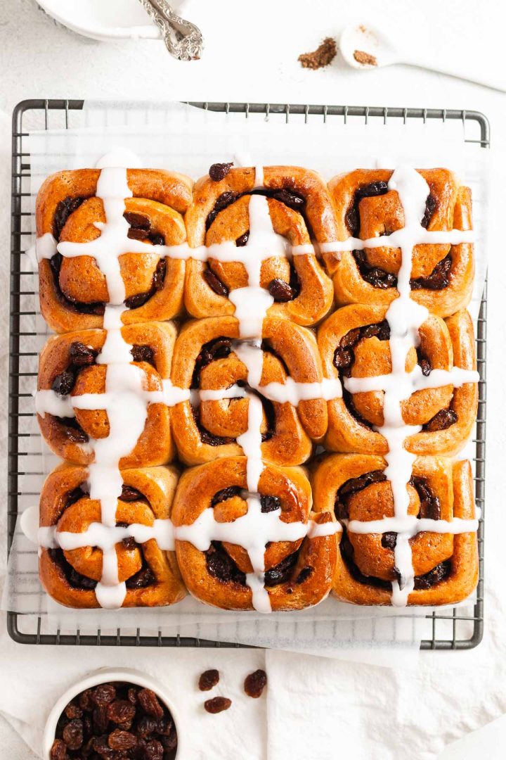 scrolls on a wire cooling rack with a small bowl filled with icing to the top.