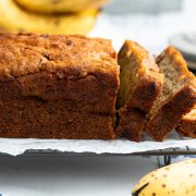 eggless banana bread on cooling rack with slices cut off the right hand side of the loaf.