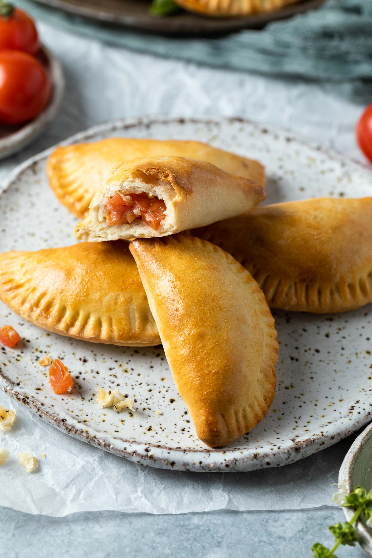 a plate of empanadas with one broken open to show the filling.