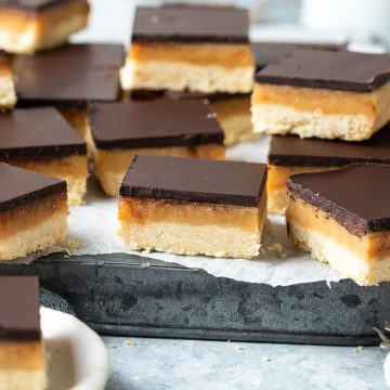 caramel slice squares on a metal baking tin, at various angles to show the layers of the slice.