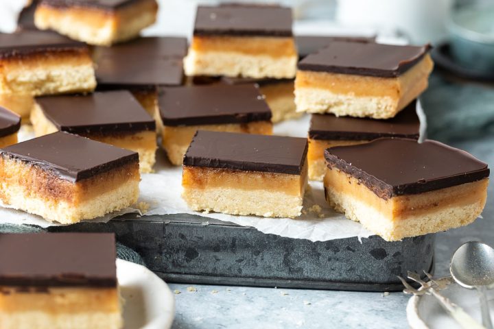 caramel slice squares on a metal baking tin, at various angles to show the layers of the slice.