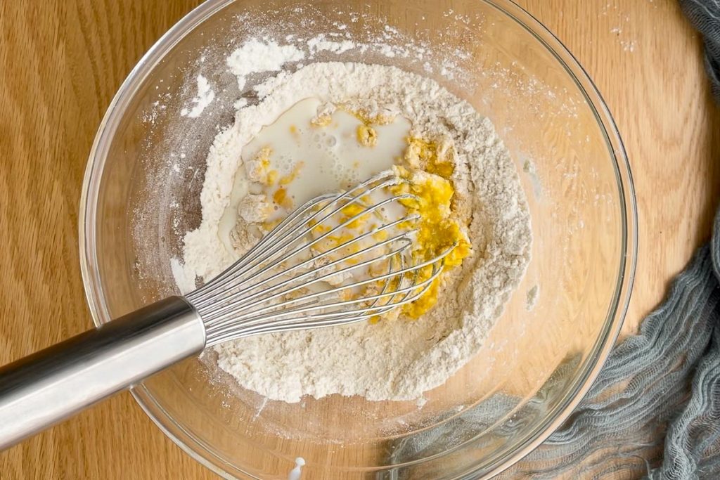 milk added to the eggs and flour in the mixing bowl.