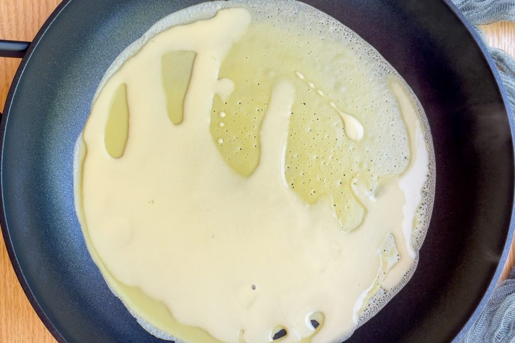 pancake batter ladled into a frying pan.