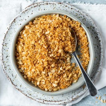 pangrattato in a blue dish with a spoon in the bowl.