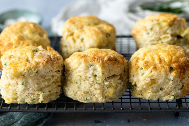 side view of 3 cheese and chive scones on a metal cooling rack.