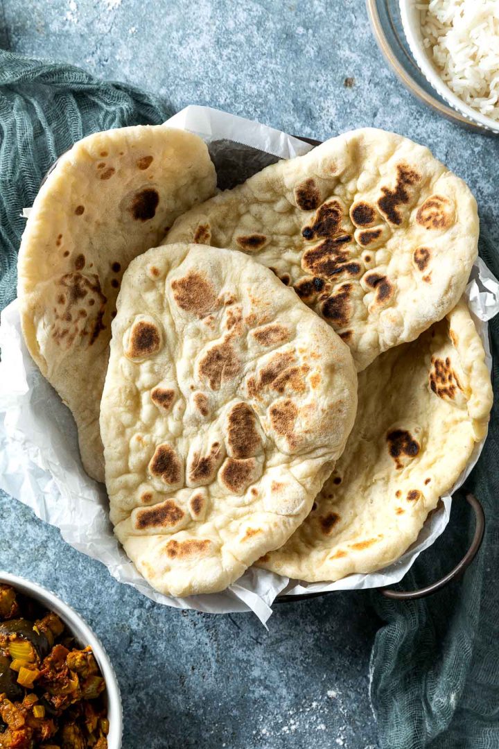 cooked naan bread on a tray with curry next to it ready to serve.