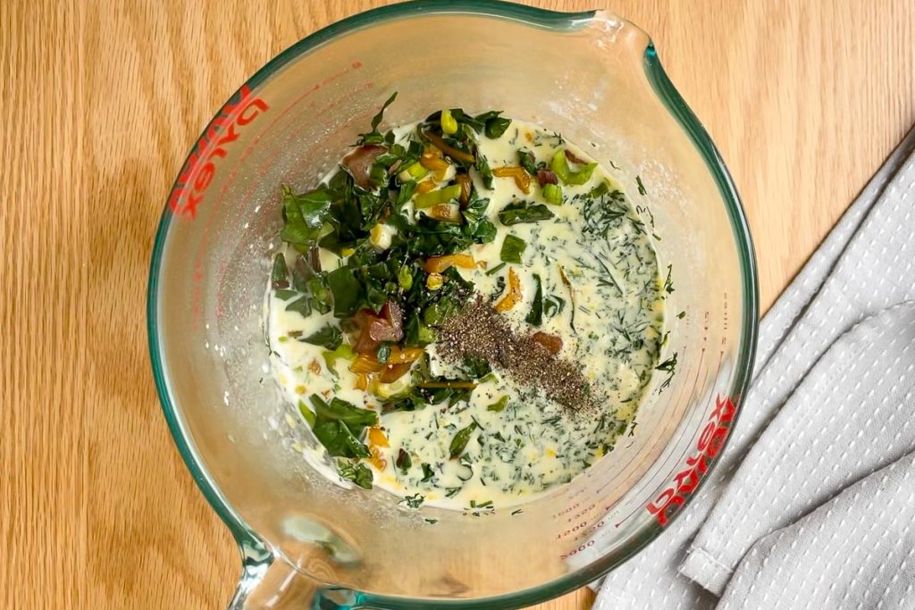 cooked silverbeet, seasonings, feta and fresh herbs added to the egg mixture in the jug.