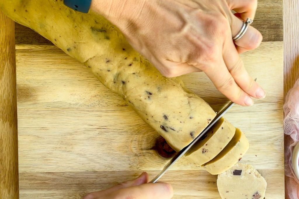 the chilled cookie dough being cut into slices.